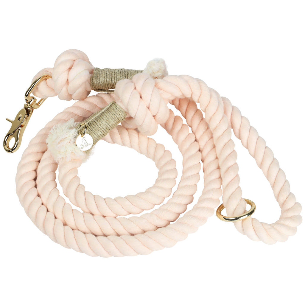 Handmade light pink cotton rope dog leash coiled with gold hardware clasp, O-ring, and Puppysentials charm, offering a soft and stylish hand-dyed artisan design.
