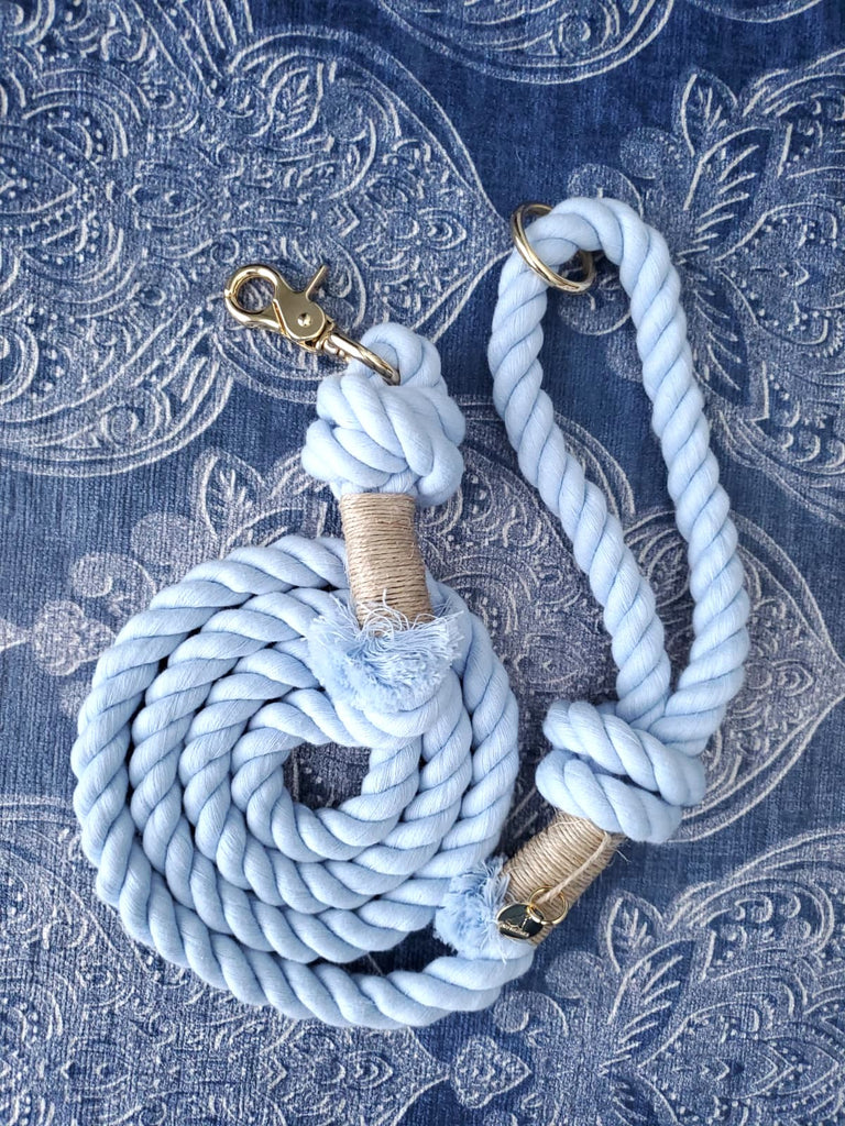 Flat lay of handmade light blue cotton rope dog leash with gold hardware on a blue patterned background.  Premium cotton rope leash for dogs by Puppysentials.